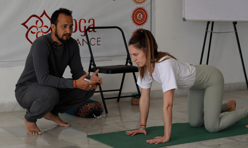 Master Yoga Instructor Providing Hands-on Alignment & Prop Adjustment on Yoga Mat
