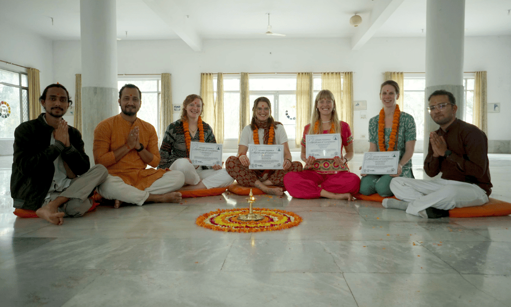 Proud Yoga Graduates Holding Yoga Alliance RYT-200 Certificates around Sacred Flower Mandala Lamp